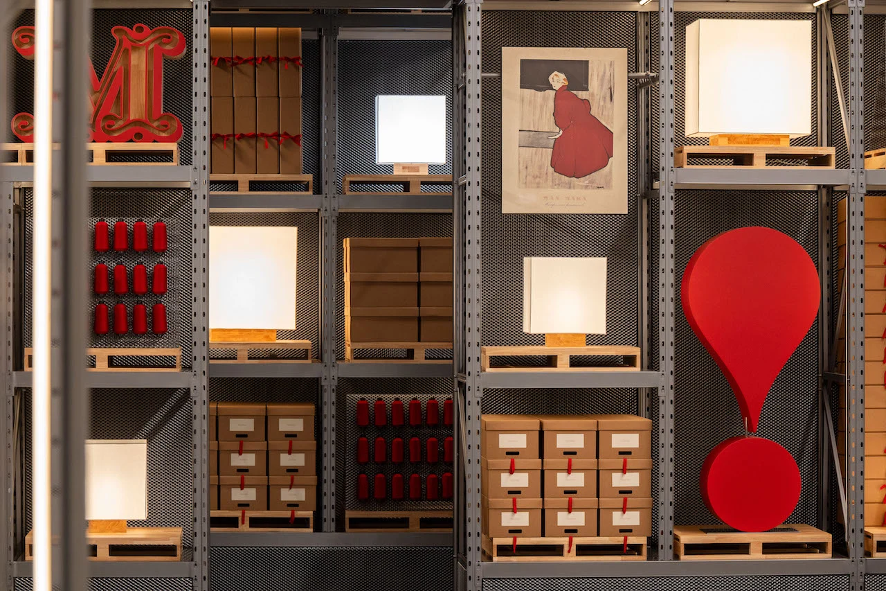 Wall of metal shelving with cube lamps, archive boxes, red spools and a large red exclamation mark – Max Mara The Max! at Long Museum, Shanghai, China, 2026 – exhibition design