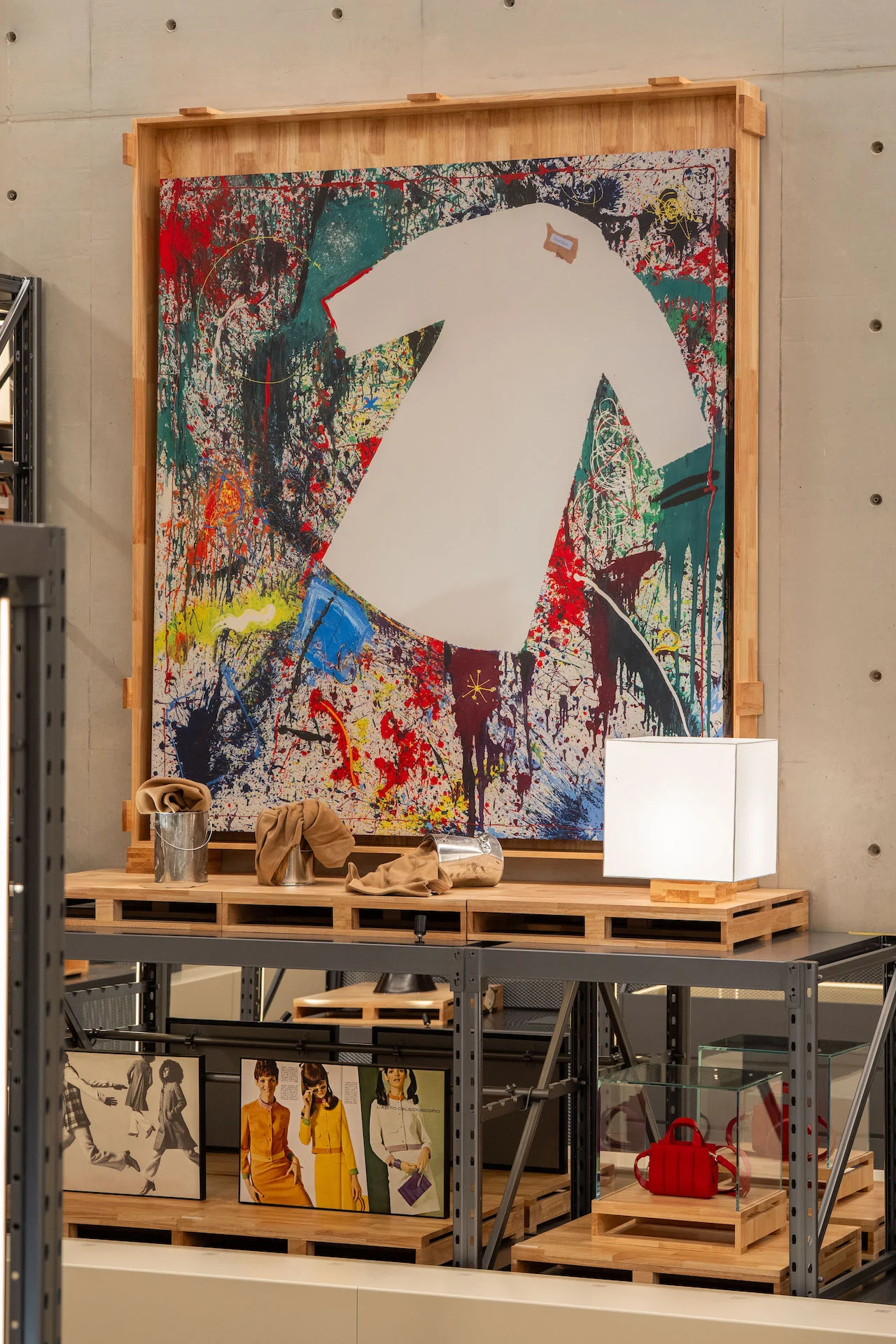Splattered painting with a white coat silhouette in a wooden frame, above shelves of accessories and photos – Max Mara The Max! at Long Museum, Shanghai, China, 2026 – exhibition design