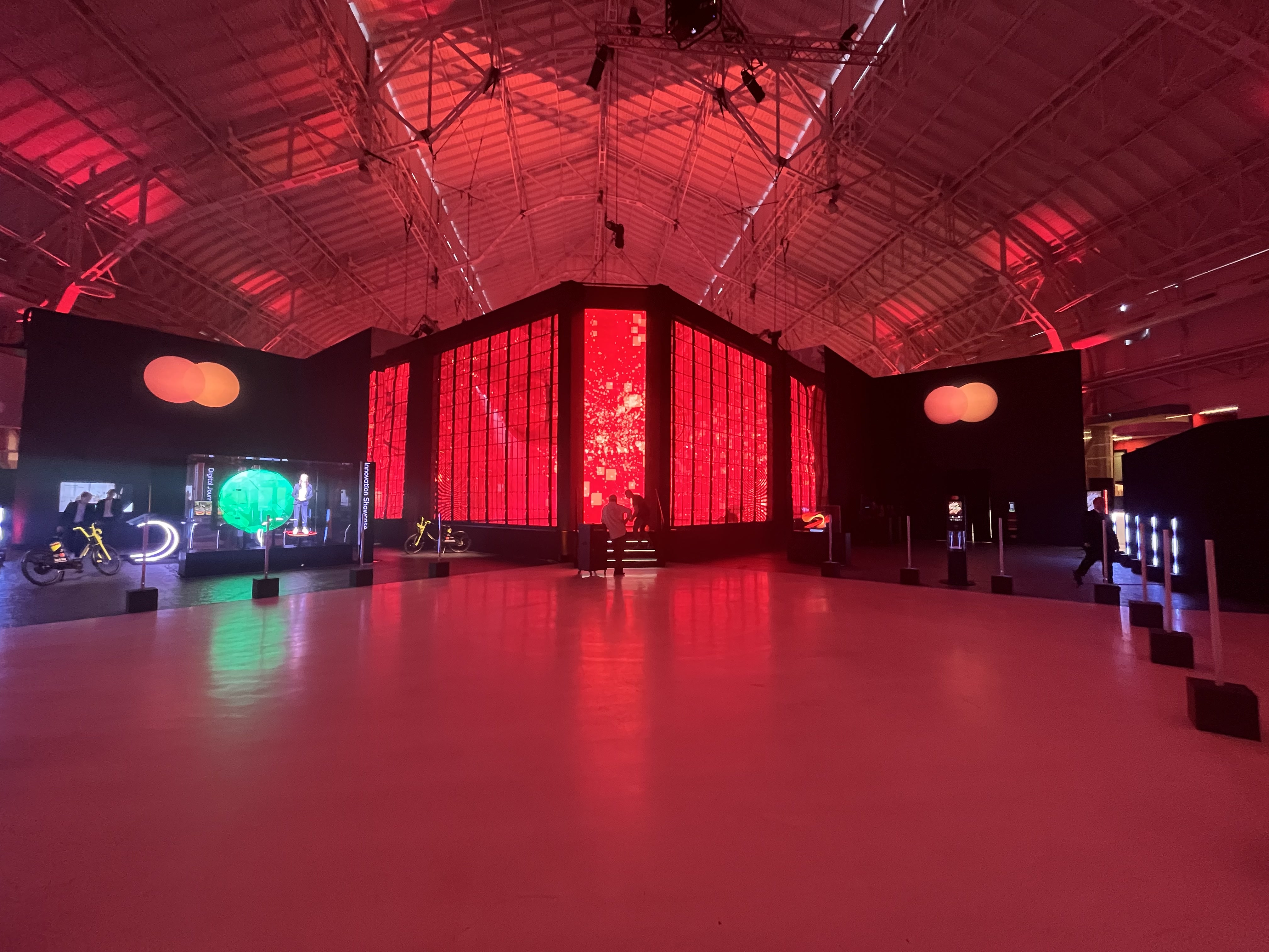 Industrial hall bathed in red light, LED wall installation at the centre and interactive stations around – Mastercard Innovation Forum 2023, Milan, Italy – event design